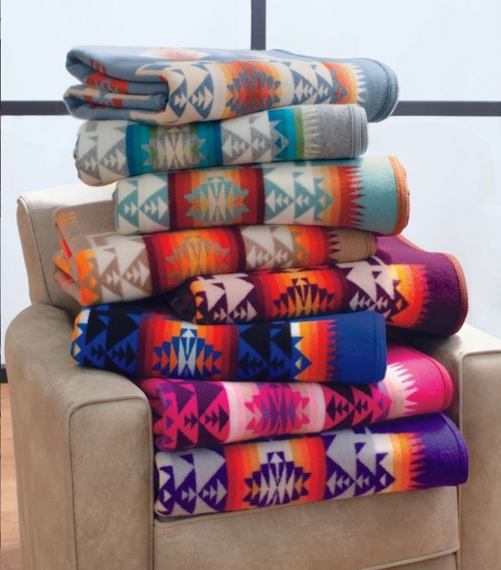 A stack of brightly colored Pendleton wool blankets in the Chief Joseph pattern on a chair