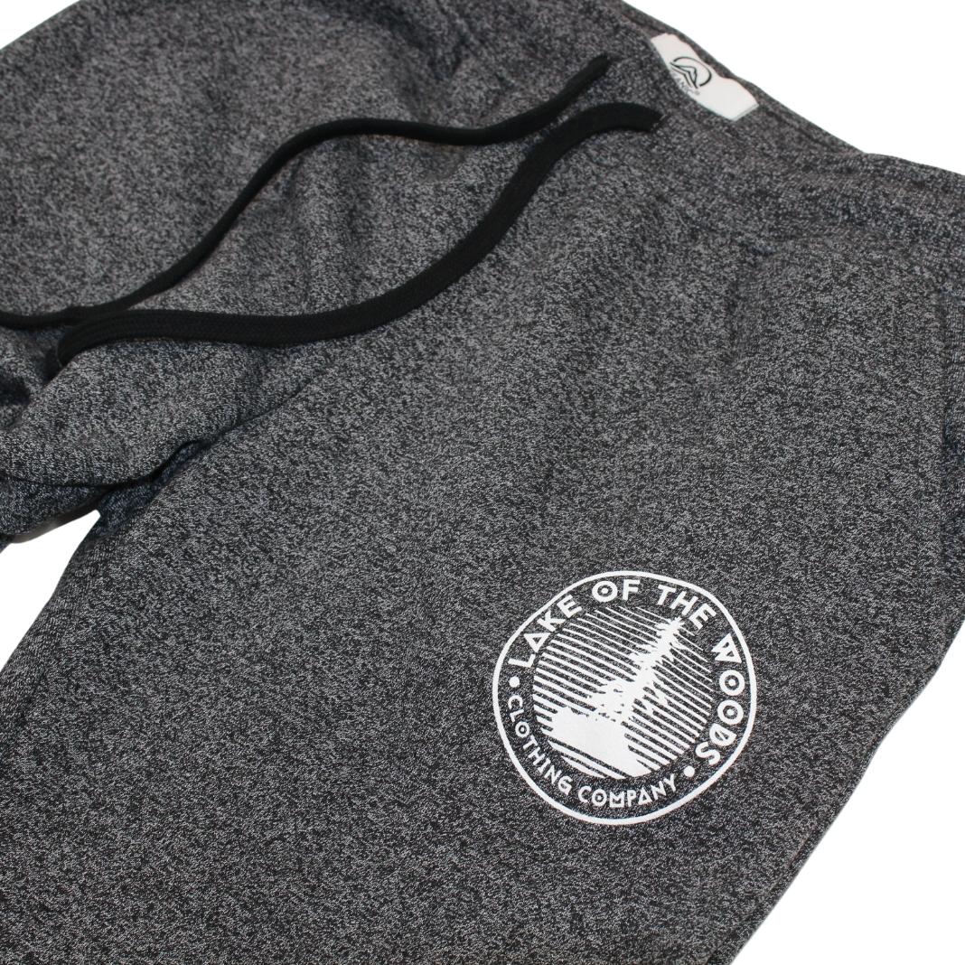 A pair of dark grey sweatpants with a Lake of the Woods Clothing Company logo design printed on the top left front leg. These sweatpants are made in Canada and are fit for women.