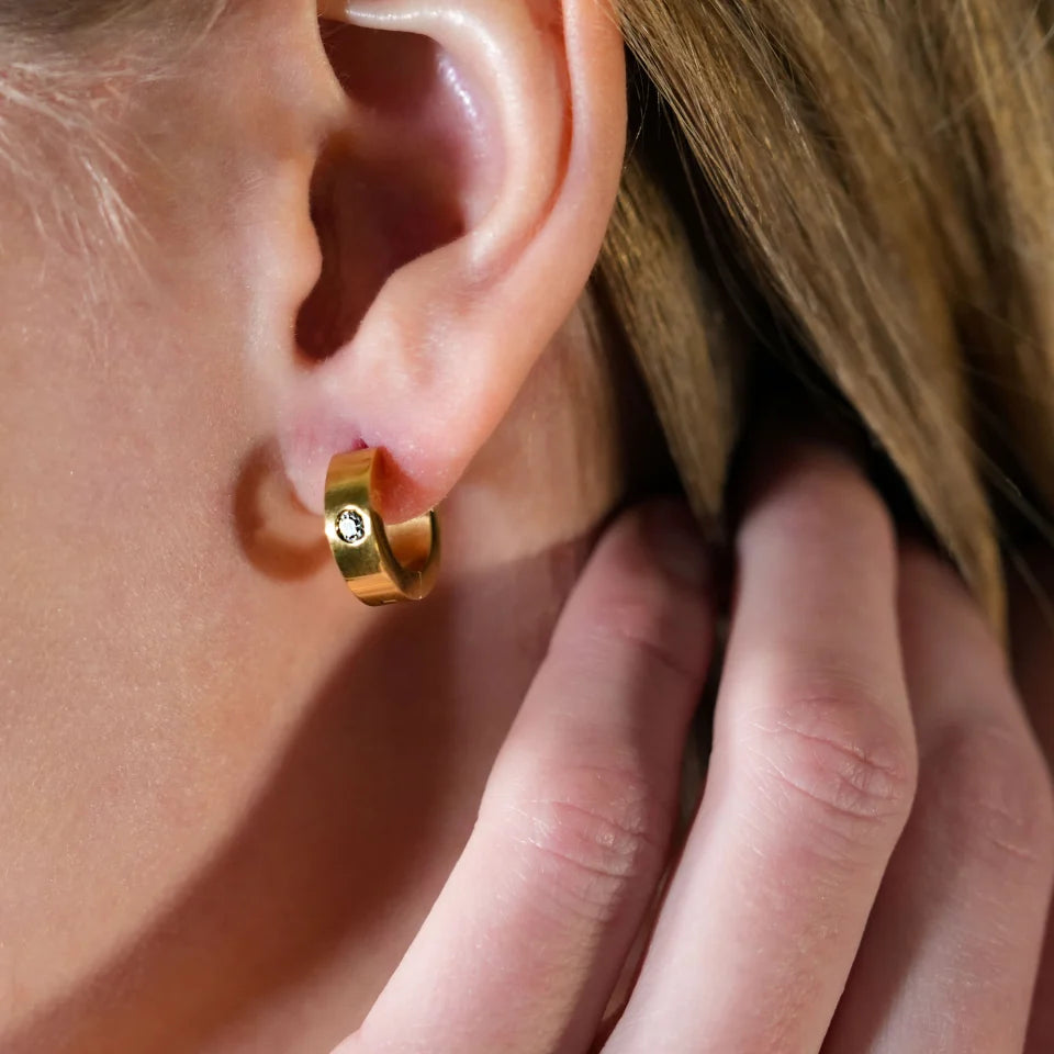 Hackney jewelry featuring a pair of gold mini hoop earrings with a solitaire zirconia gemstone.