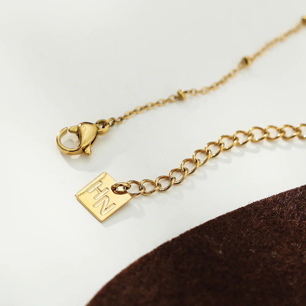Hackney jewelry featuring a gold necklace with delicate beaded chain and gemstone charm