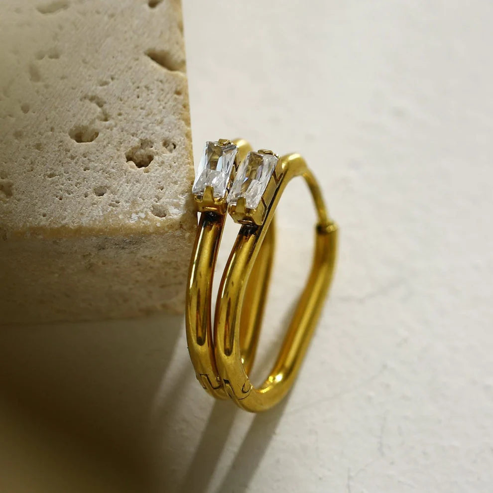 Hackney jewelry featuring a pair of gold hoop earrings with a solitaire rectangle zirconia.
