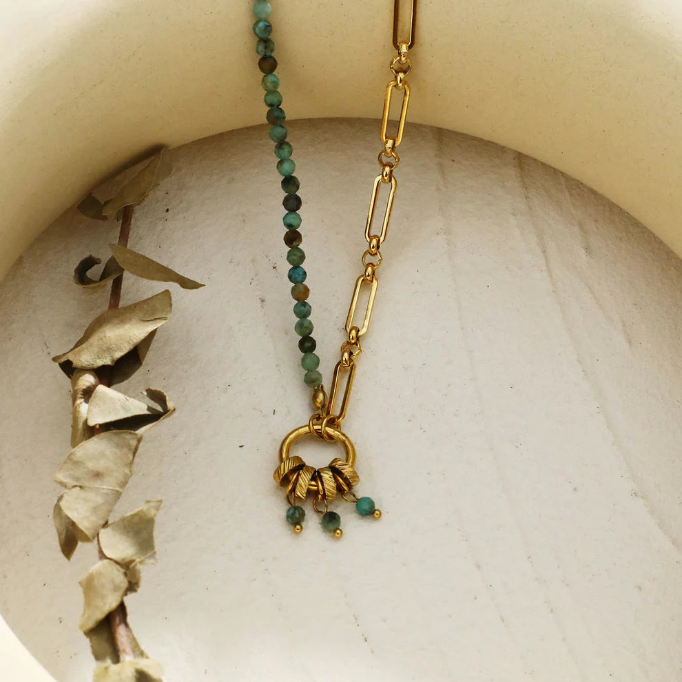 Hackney jewelry featuring a turquoise natural sone charm pendant on gold necklace.