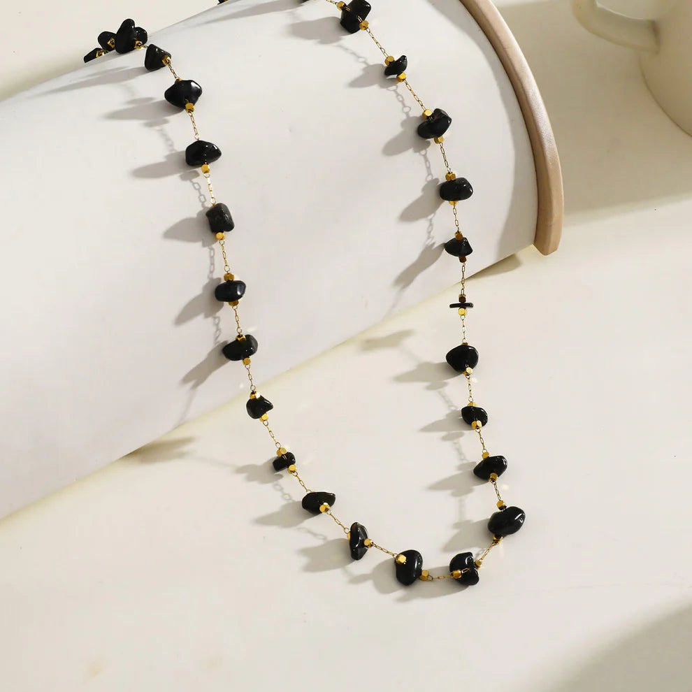 Hackney jewelry featuring a gold necklace with mini beads and natural black stones.