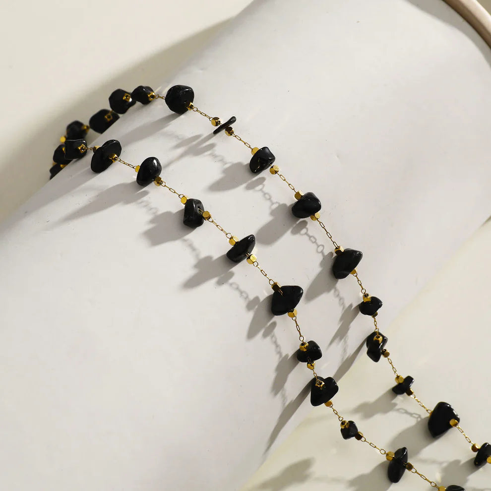Hackney jewelry featuring a gold necklace with mini beads and natural black stones.