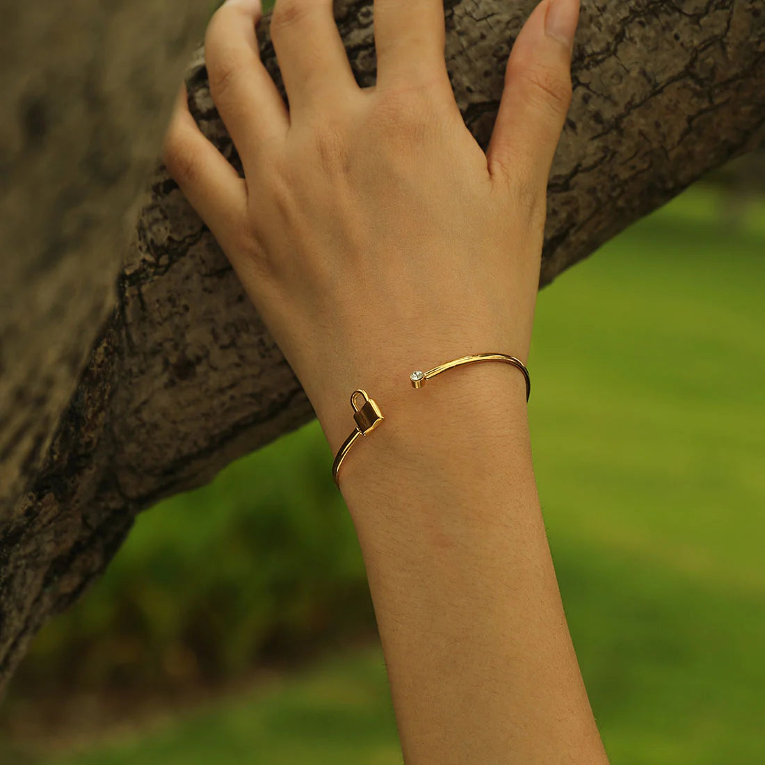 Hackney jewelry featuring an open adjustable gold bracelet with a sparkling gemstone on one end and a lock on the other.