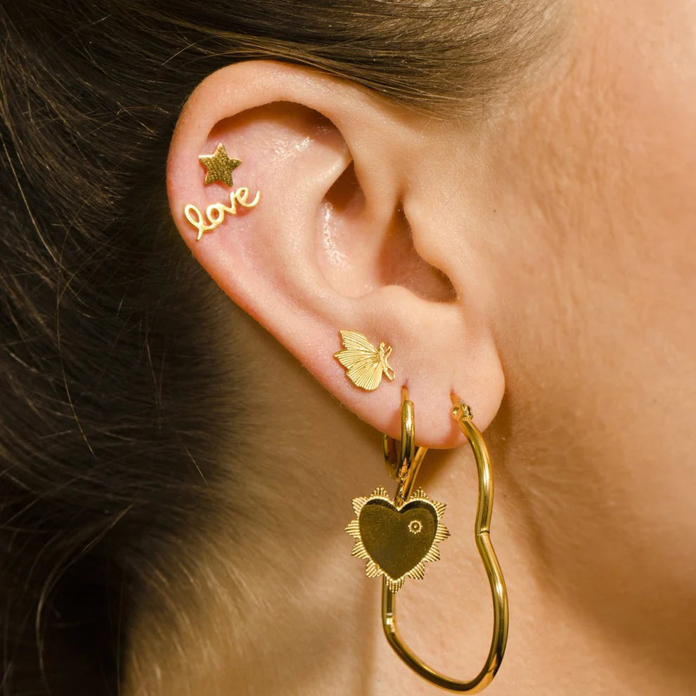 Hackney jewelry featuring a pair of gold heart hoop earrings.