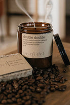 Candle with coffee beans on a wooden surface, featuring canadian made candle.