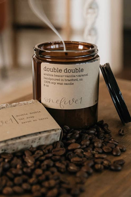 Candle with coffee beans on a wooden surface, featuring canadian made candle.