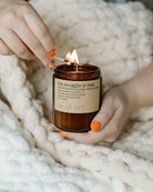 Person holding a lit candle wrapped in a cozy blanket