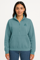 Woman wearing a teal quarter-zip sweatshirt with “Lake of the Woods” logo on the left chest, standing against a plain white background.