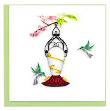 Perfect card for love, good luck and joy  for an occasion handcrafted with a hummingbird feeder hanging from a pink flowery branch with two green and gray hummingbirds hovering around the feeder.