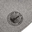 A circular outline with the text Lake of the Woods Clothing Company curved around the circle with a tree silhouette on the interior.