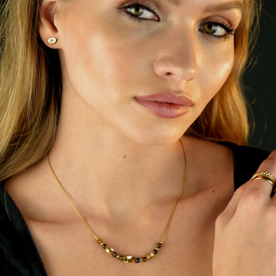 Hackney jewelry featuring a snake skin textured chain necklace with gold and tiger eye stone charms. 