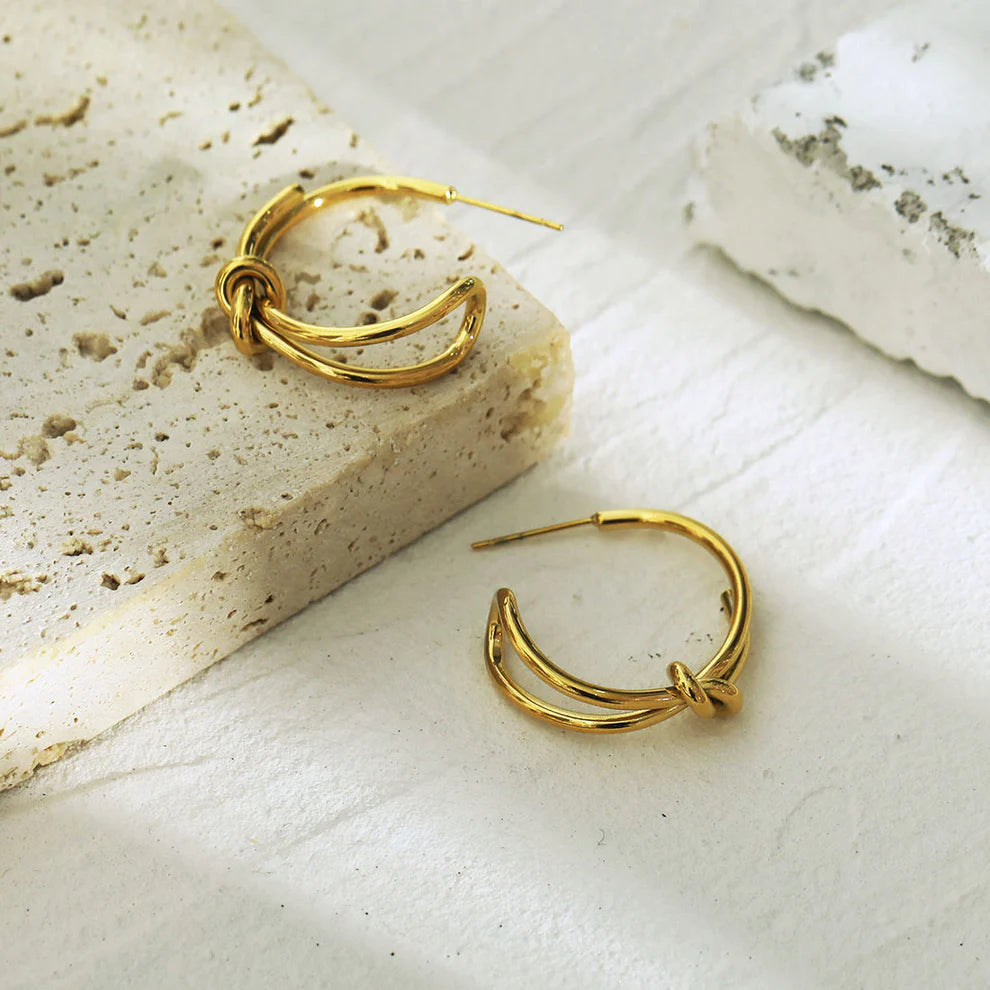 Hackney jewelry featuring a pair of abstract gold hoop earrings