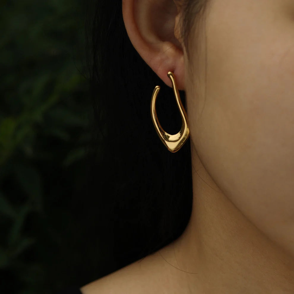 Hackney jewelry featuring a pair of abstract shaped gold hoop earrings.