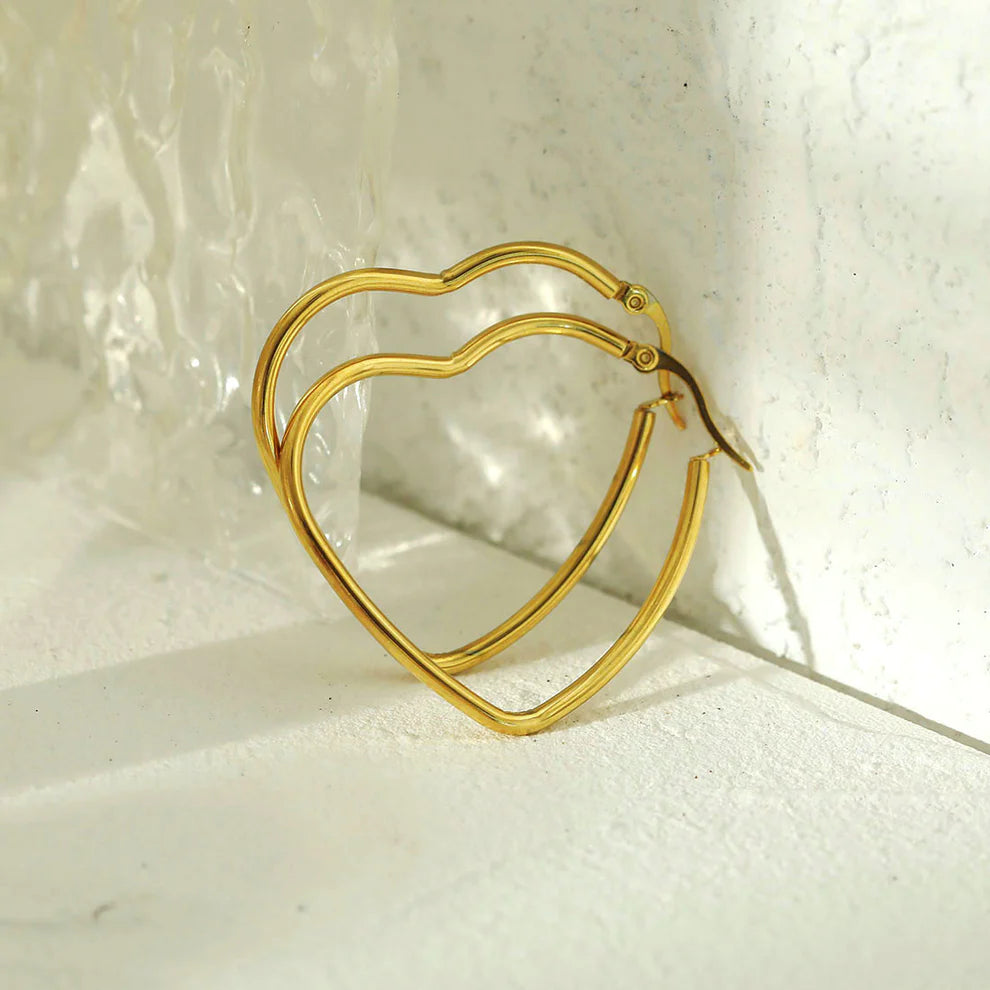 Hackney jewelry featuring a pair of gold heart hoop earrings.