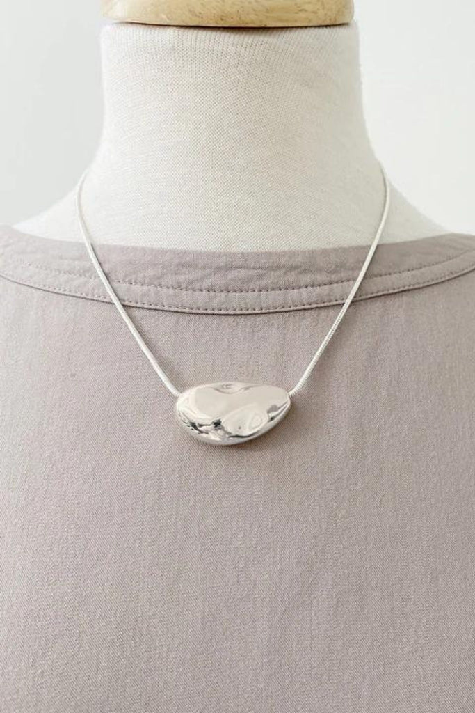 Caracol jewelry featuring a textured metallic pendant on chain necklace