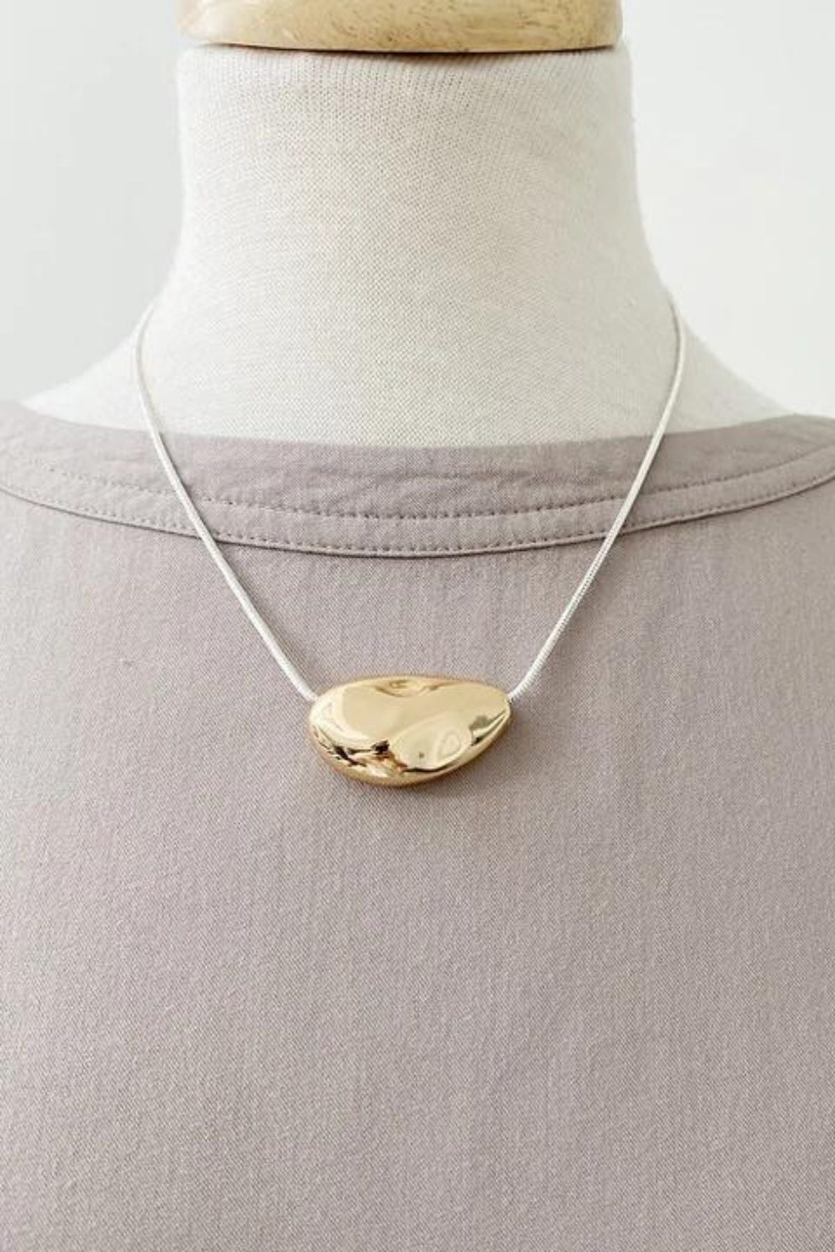 Caracol jewelry featuring a textured metallic pendant on chain necklace